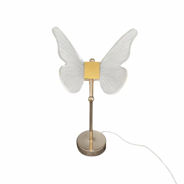 Elegant butterfly-shaped table lamp glowing with warm white light on a nightstand in a Dubai bedroom at dusk