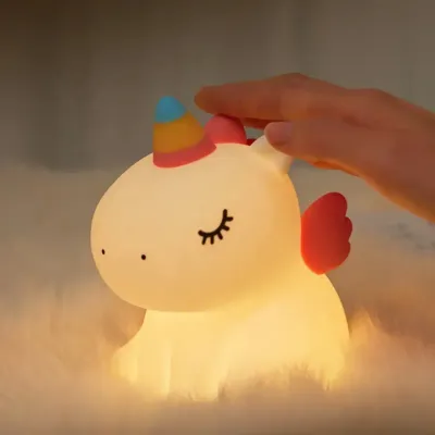 Cute unicorn night light glowing with warm white light on a pastel-themed bedside table in a Dubai nursery